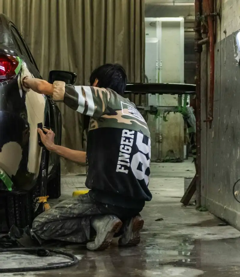 Carrossier ponçant une aile avant la mise en peinture